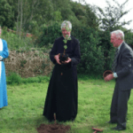 Rev. Roy Fowler and Geoff Knapp look on while Rev. Jim Hawkins plants a birch tree.